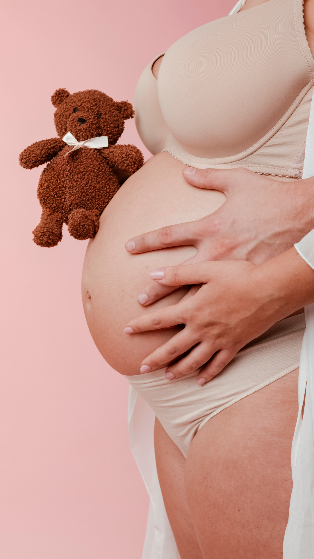 Donna in dolce attesa che tocca dolcemente il pancione mentre sorregge un pupazzetto "Teddy Bear" vicino a lei. Nel mentre una mano di uomo tocca il pancione a dare senso di sicurezza 
